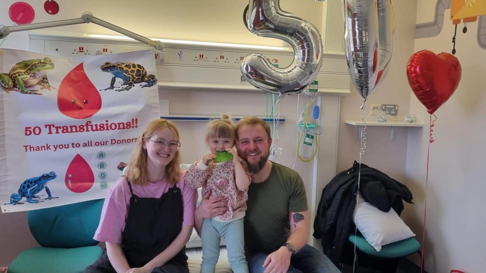 A four-year-old girl in a hospital room with her parents
