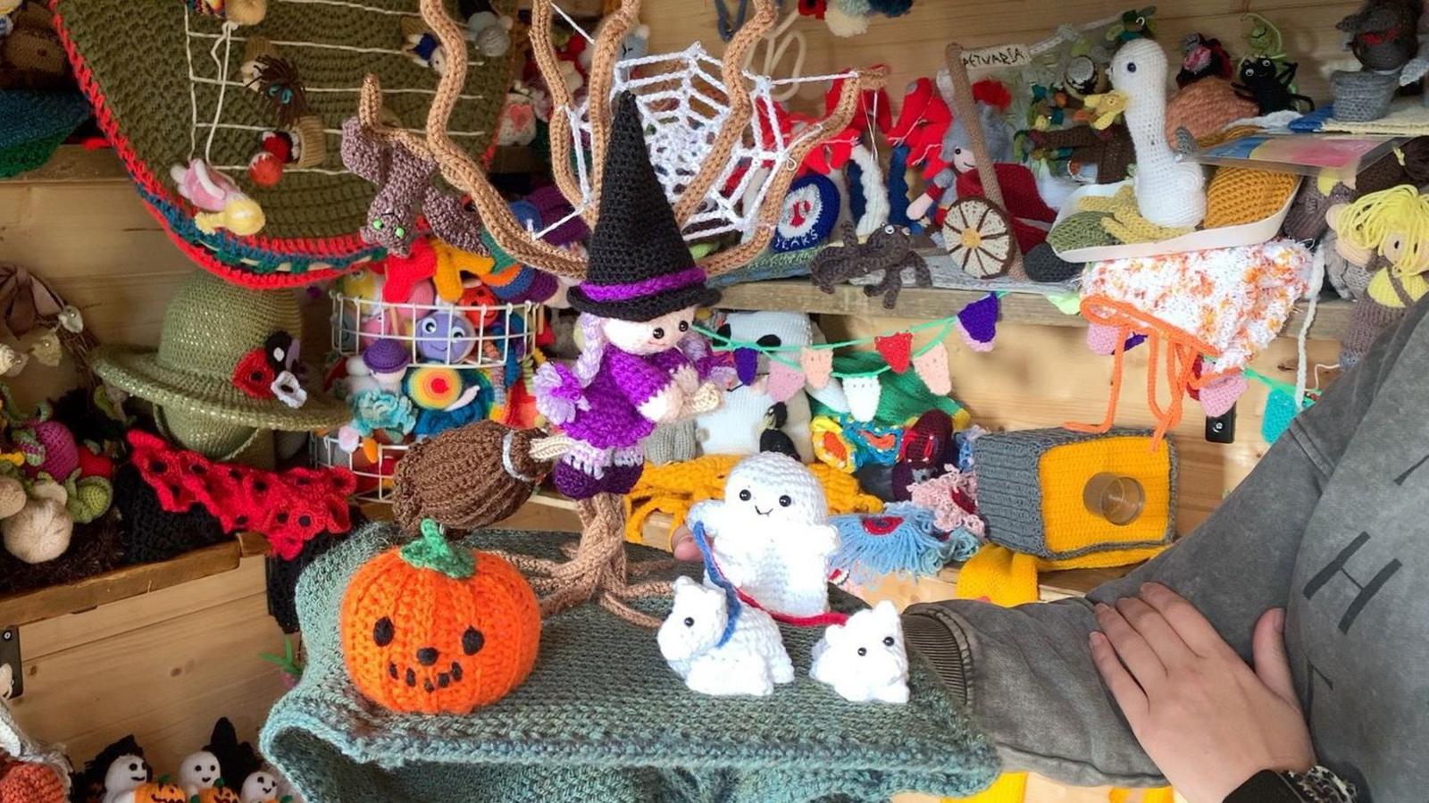 A knitted witch, pumpkin and ghosts, among a large collection of woollen "toppers" inside a wooden shed