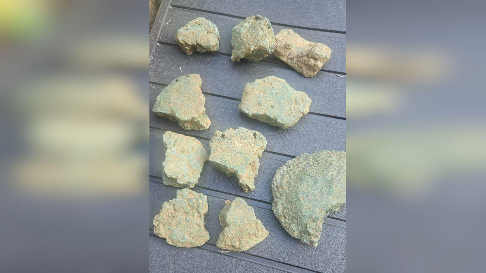 Several lumps of old metal are laid out on a table. 