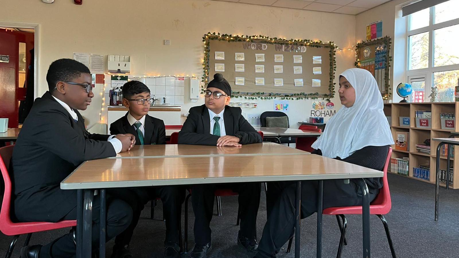 Four children sit around a table talking