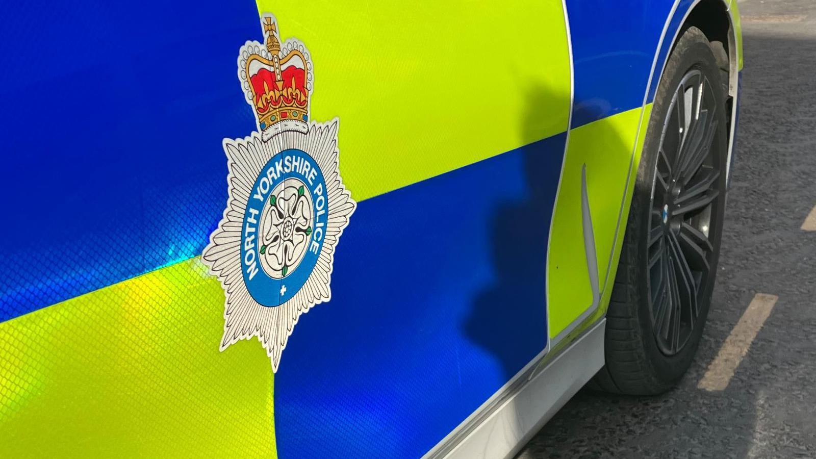 Police car with fluorescent blue and yellow markings and a North Yorkshire Police emblem