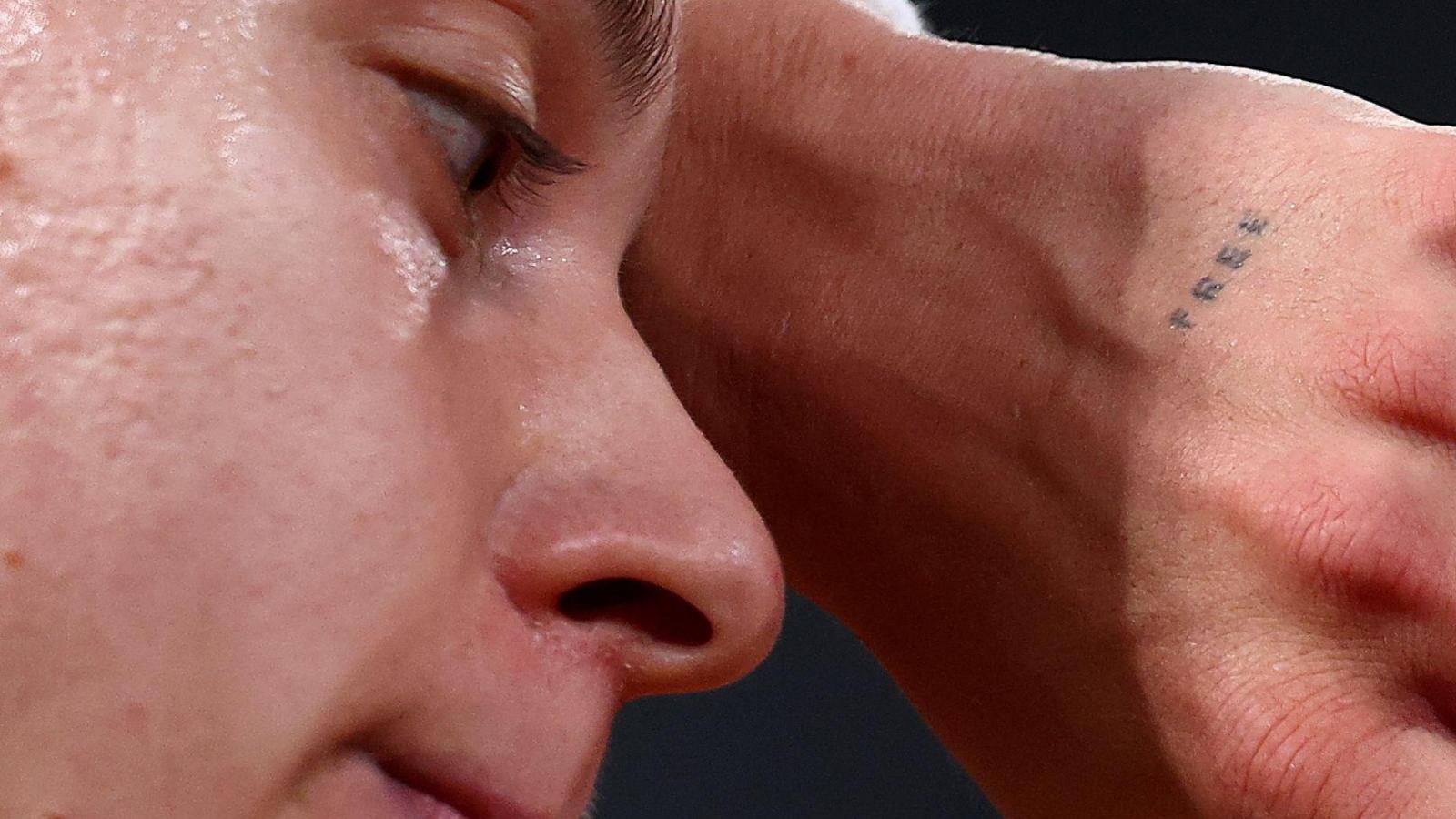 A close up of Maja Chwalinska's face with a tiny tattoo reading "free" just visible on her hand