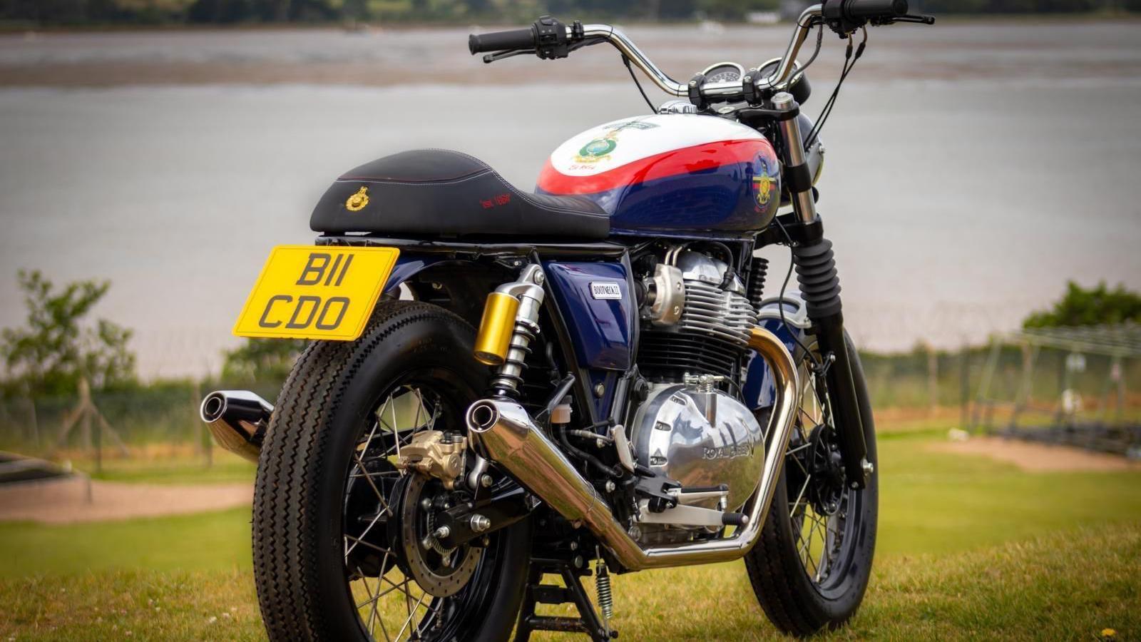 A motorbike on green grass. There is a river in the background that is blurred.
