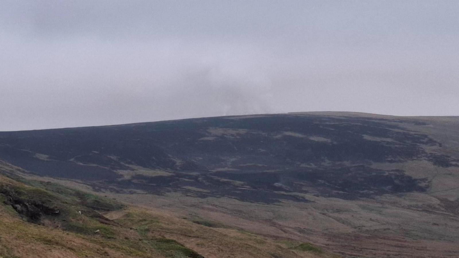 A shot of moorland at dawn with some slight smoke drifting from the top of the moor