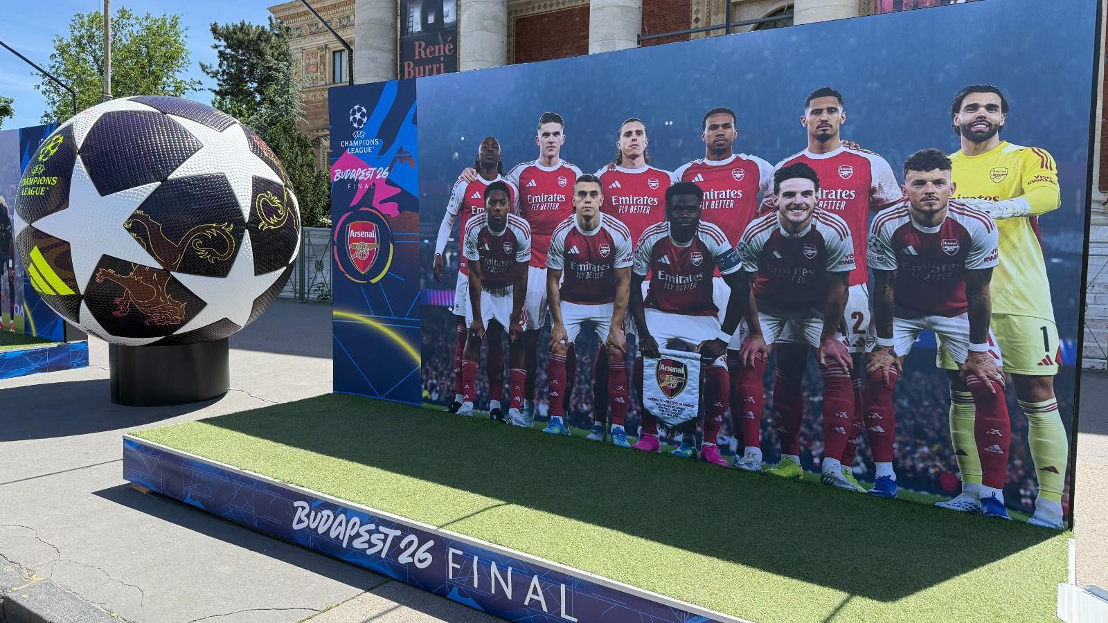 A life-size picture of Arsenal players lining up before a game on a small platform in Budapest