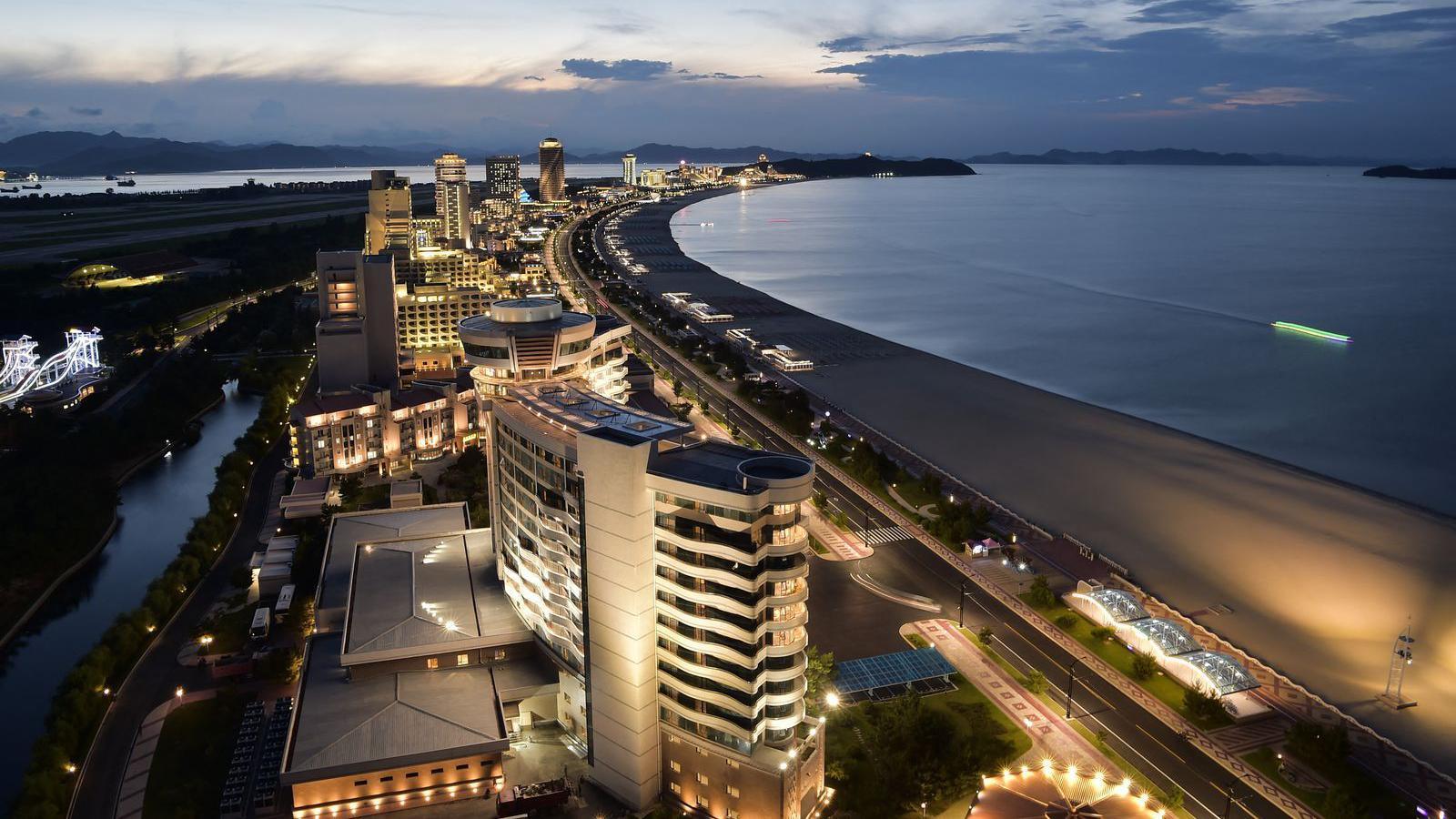 The Wonsan Kalma Coastal Tourist Area in Wonsan. A series of multi-story buildings are visible in the image, which all sit along the shoreline.