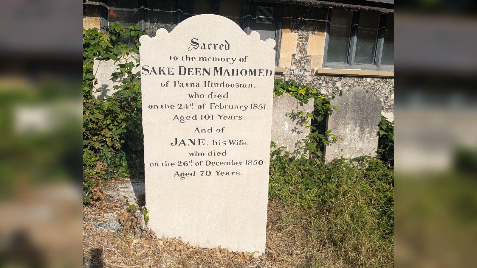 An old gravestone that has been freshly cleaned and restored. The sun is shining.