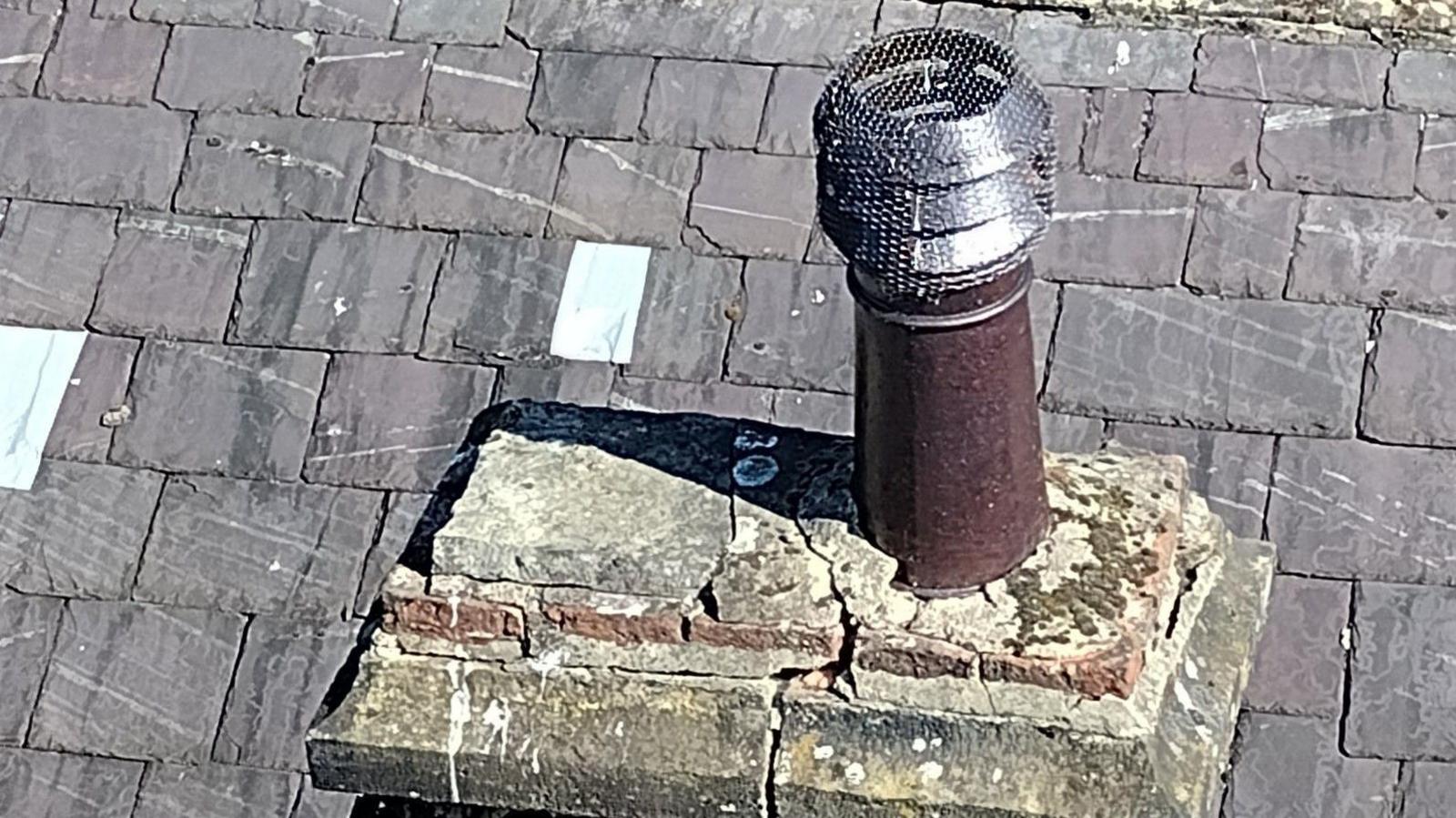 A slate roof with a crumbling chimney stack, taken from above.