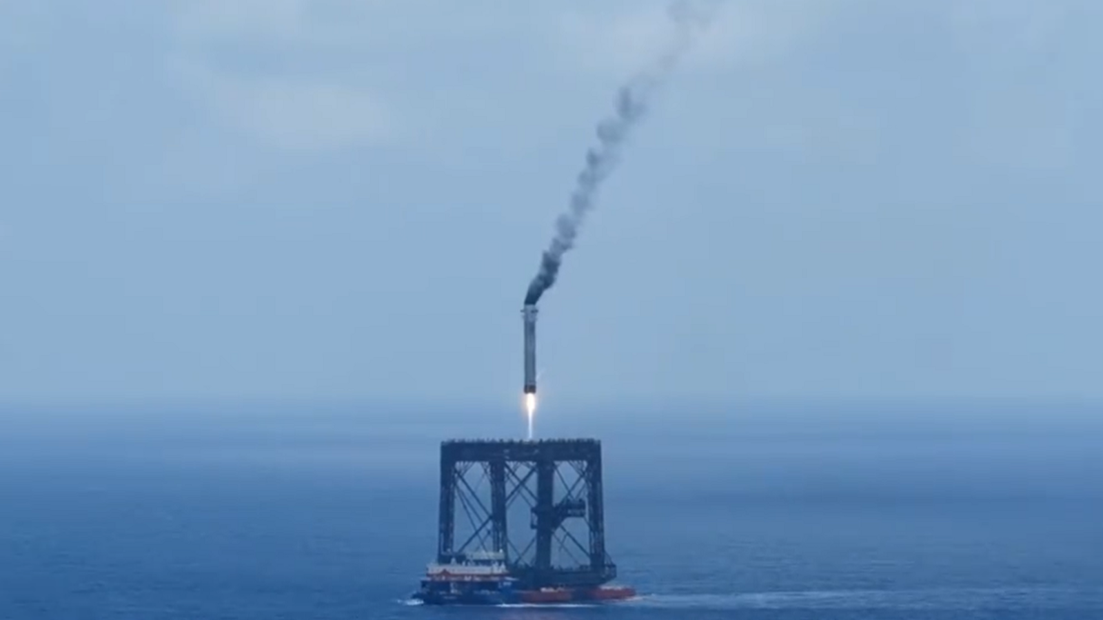 A screengrab of a Long March 10B booster rocket landing on a recovery platform.