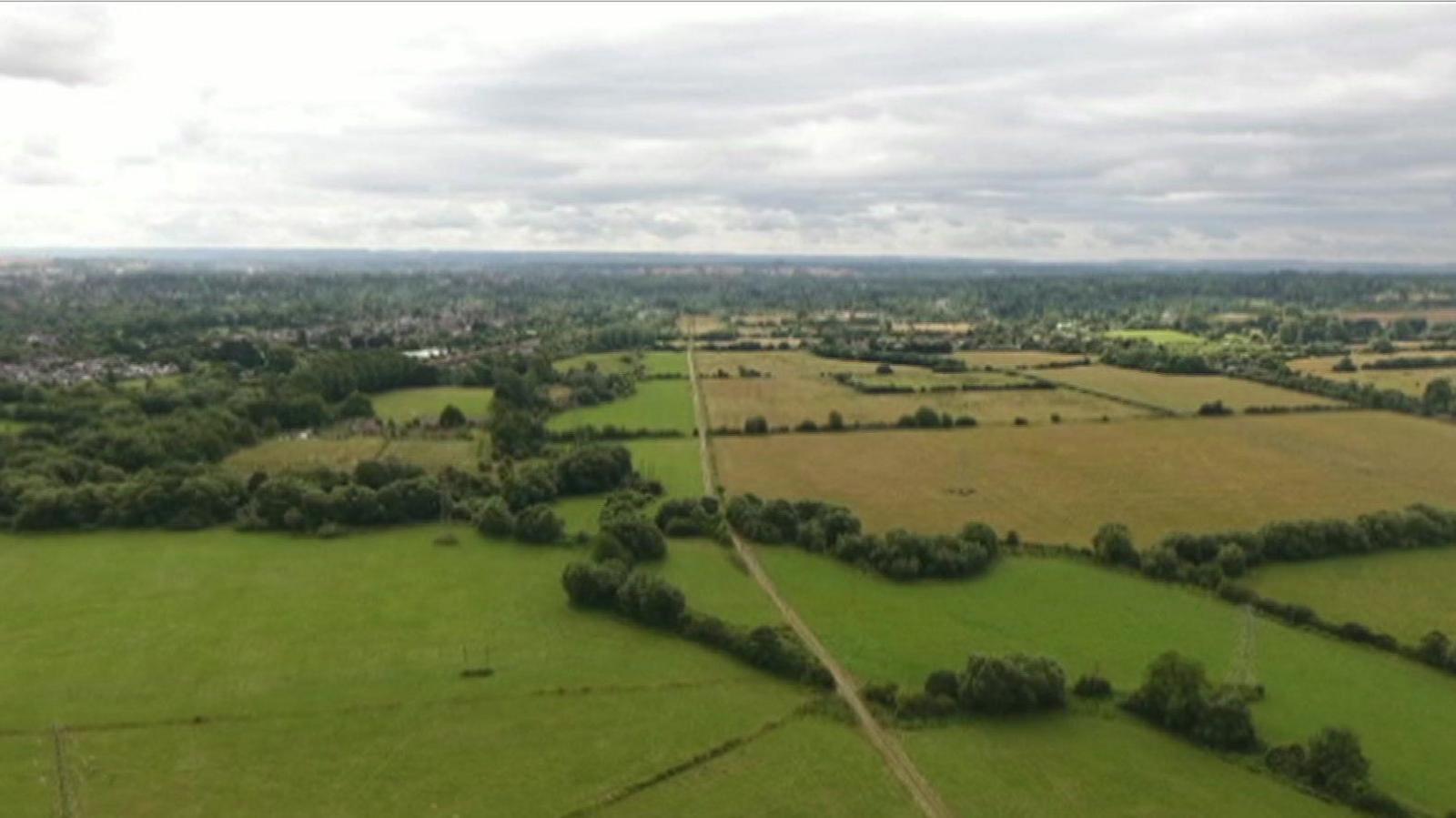 An aerial showing green fields in Oxfordshire, with a road running up the centre of the picture.