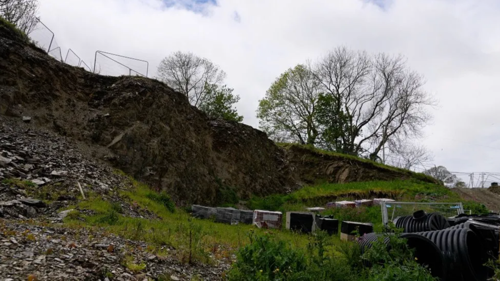 Lock's Hill in Kingsbridge, Devon, with construction materials at the bottom of a slope and fencing at the top of it