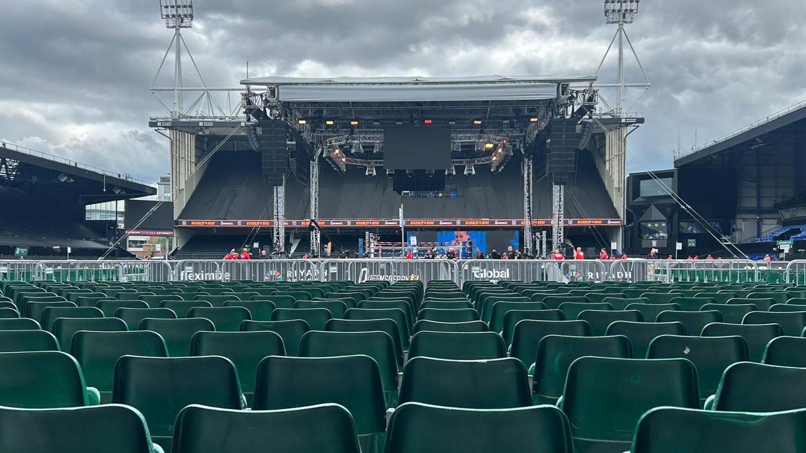 Seats in the foreground at Portman Road, with a stage in the centre of the pitch, that has a boxing ring in the middle with big screens that will broadcast the fight. Behind the boxing ring is one of the stands at the stadium.