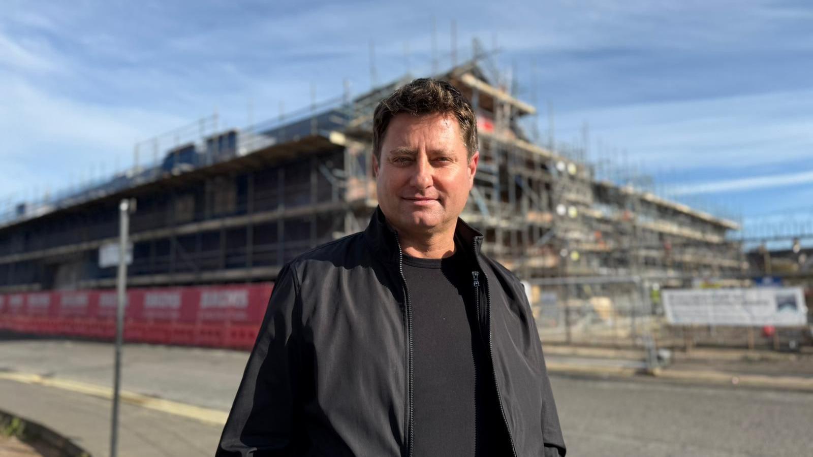 George Clarke in front of the HICSA. The building has scaffolding around it and is located just a stones throw from the sheepfolds leisure complex.