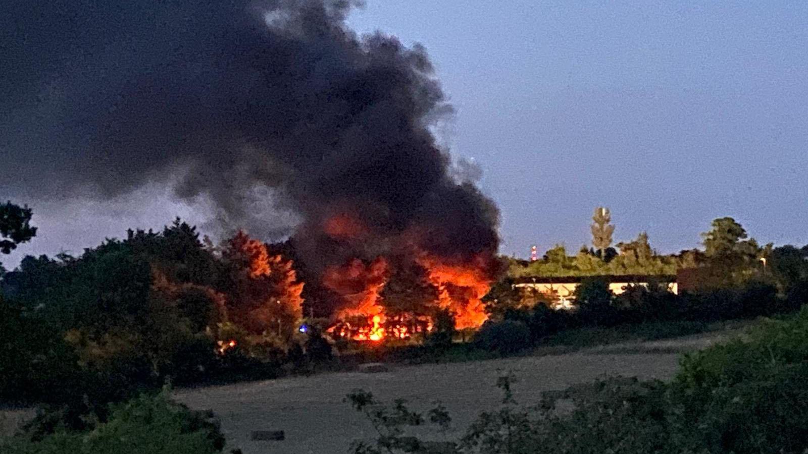 The skip lorry site in College Road, Epsom on fire, with thick black smoke and flames filling the air.