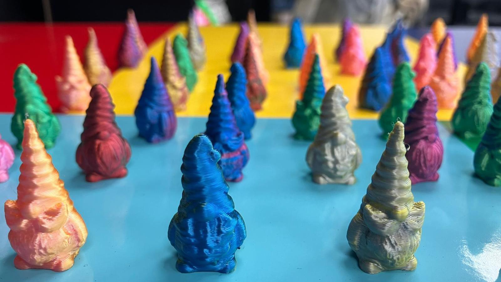 A table full of tiny gnome figures in an array of different colours. The gnomes have tall pointed hats and large beards.
