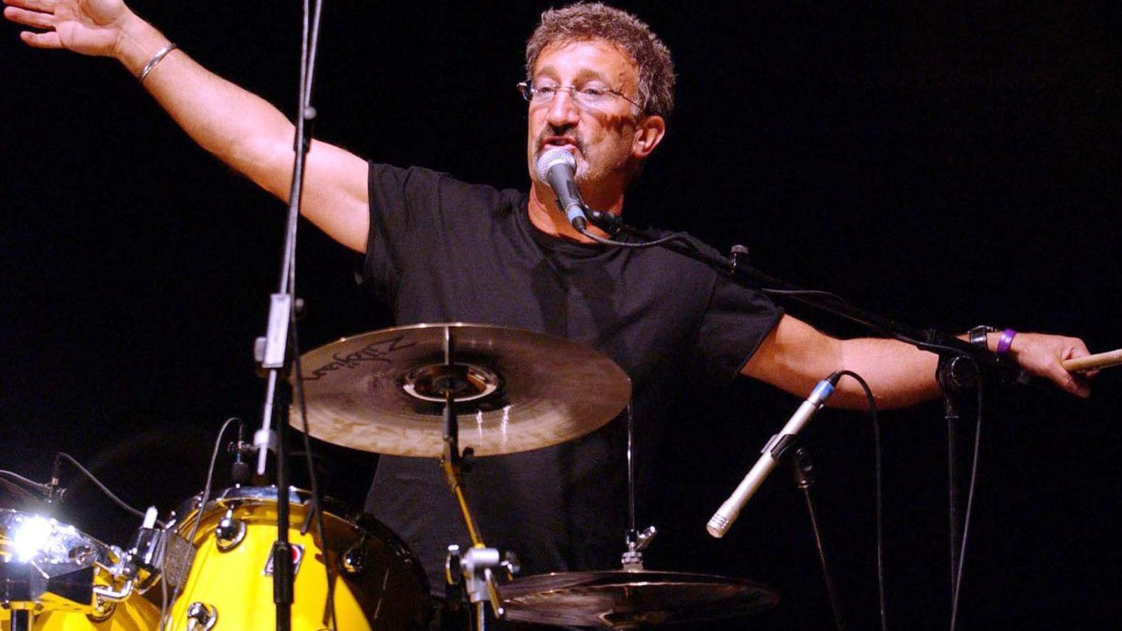 Eddie Jordan with his arms outstretched while playing the drums