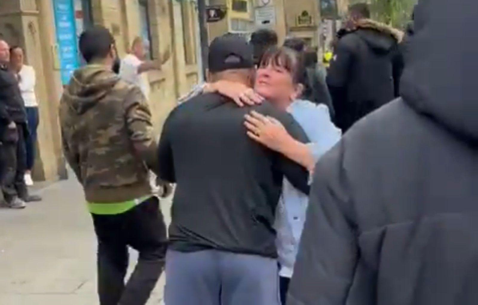 A peaceful Muslim counter-protester and a woman embrace outside a pub in Accrington.