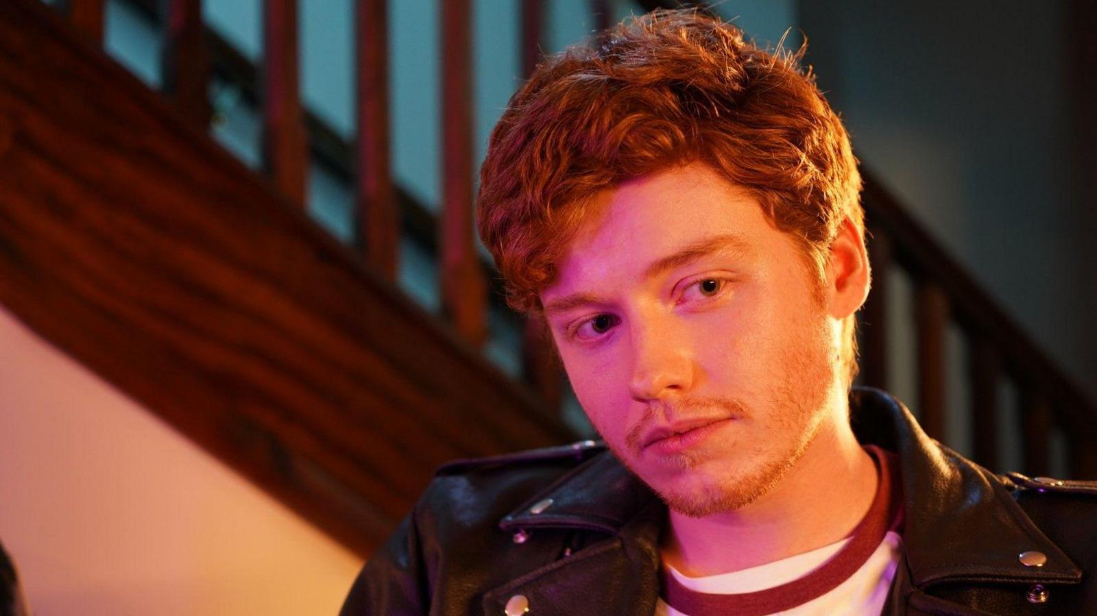 Llun o'r actor Gwion Morris Jones sy'n chwarae rol Carbo. Mae ganddo wallt sinsir. Mae e'n gwisgo crys gwyn gyda siaced du.