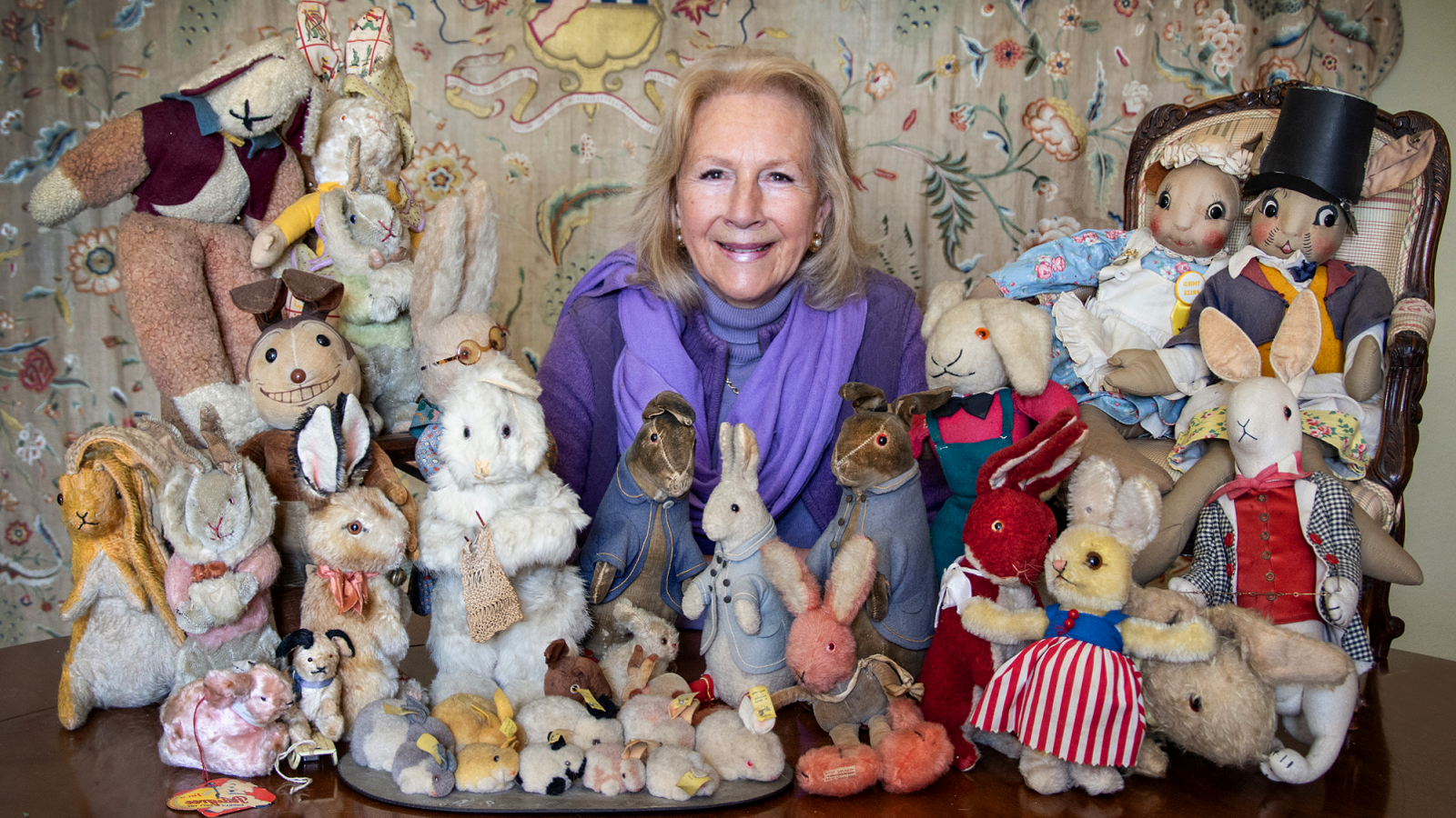 Bunny Campione, wearing a purple top and scarf, sat with the rabbits of various shapes and sizes.