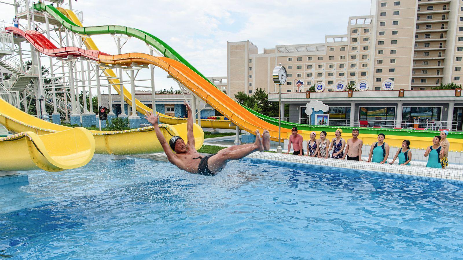 Domestic tourists watch as a man uses a slide into a swimming pool at the Myongsasimni Water Park in the Wonsan Kalma Coastal Tourist Area in Wonsan, North Korea's Kangwon Province.
