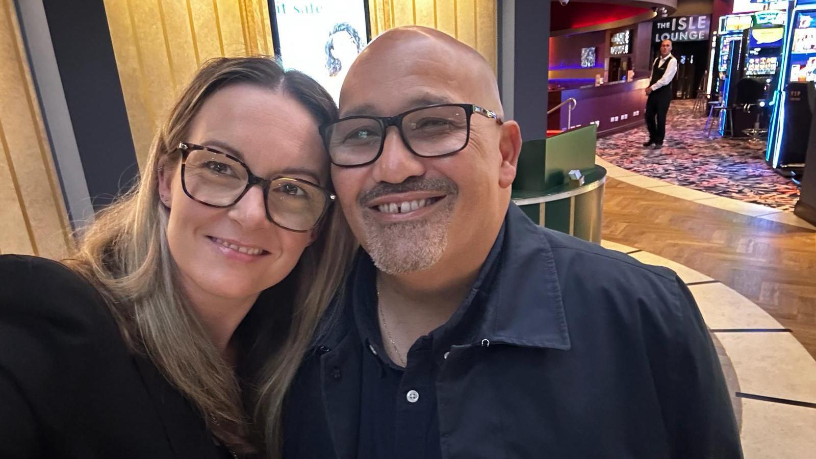 Smiling man and woman cuddling together and lookin to camera indoors
