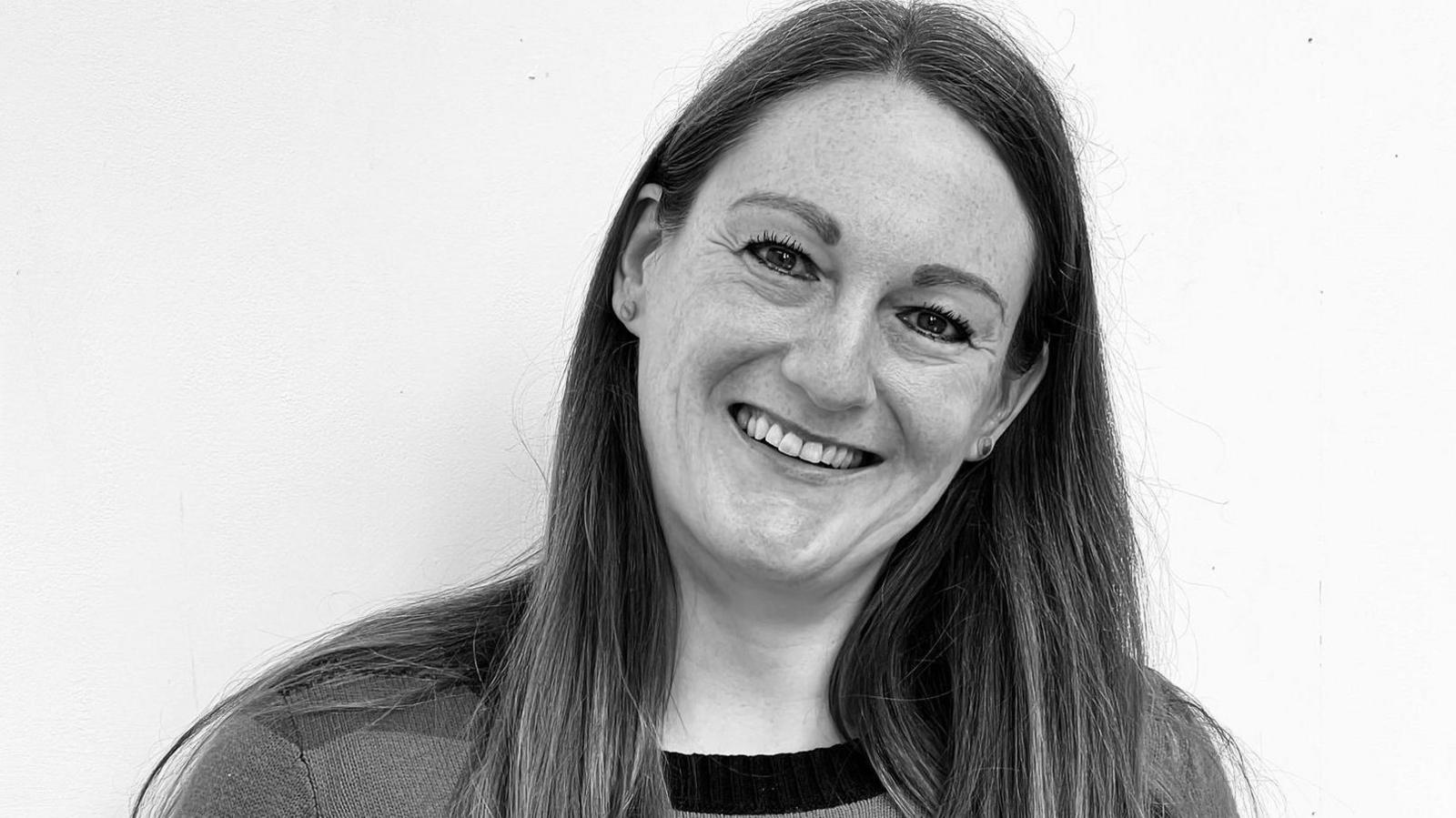 Helen Gordon has dark brown hair and is smiling at the camera. It is a black and photo profile shot.