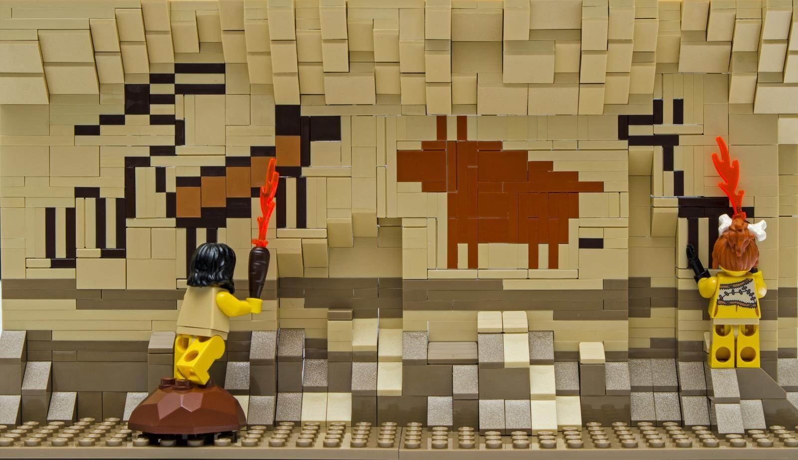 Lego artwork depicting two yellow figures painting animals on the wall of a cave.