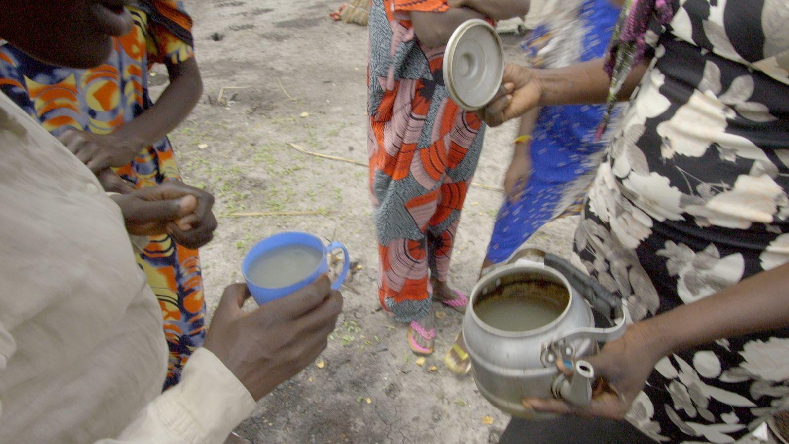  Women show pale grey water in a kettle and a cup in Roriak, South Sudan