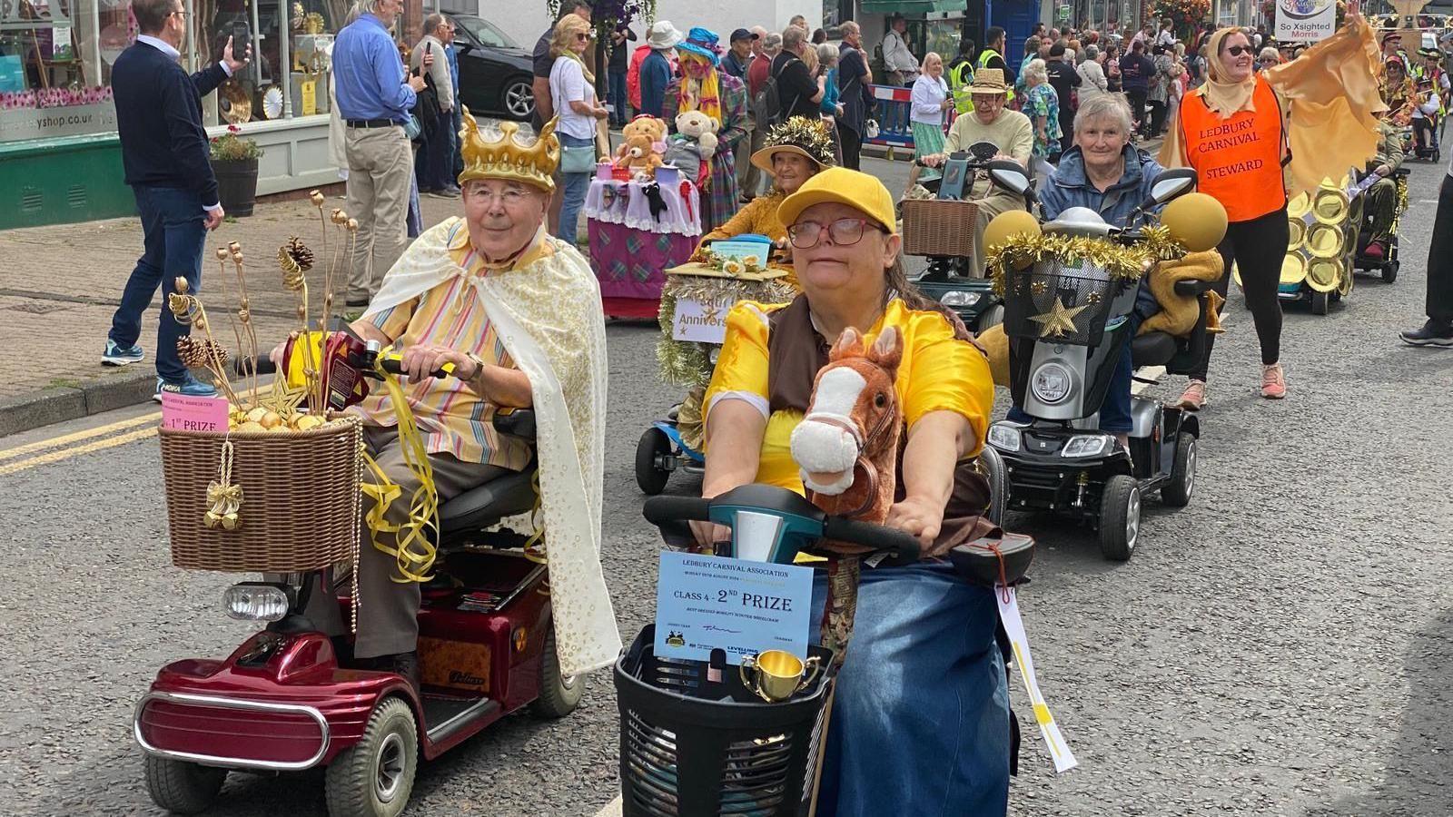 People on mobility scooters wearing yellow take part in the carnival procession.
