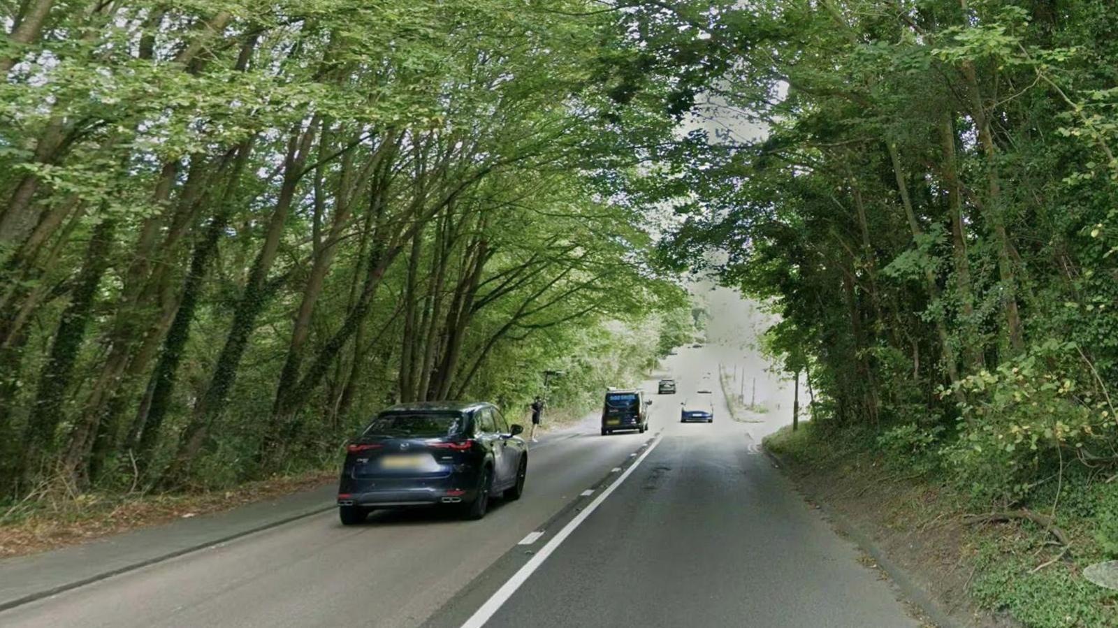 A general shot of the A23 at Redhill with cars on it and tree-lined road