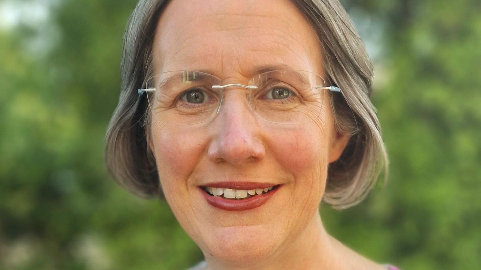 Ann Watt, she is smiling at the camera and is wearing glasses.