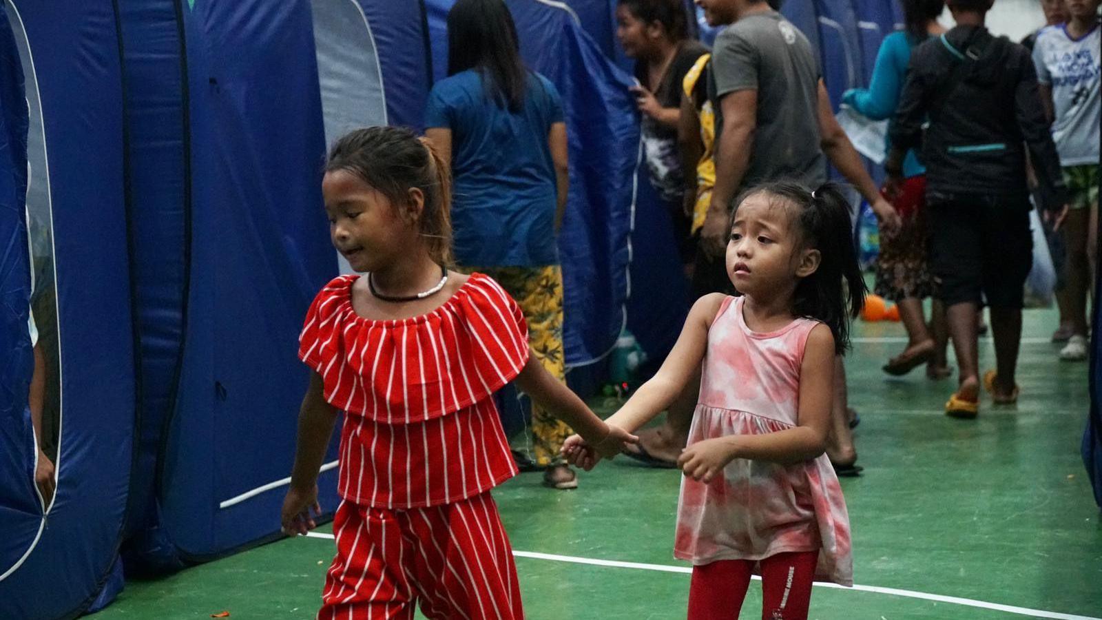 Two girls walk around at a shelter in central Aurora in eastern Luzon