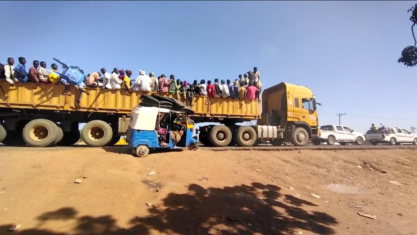 People sitting on the back of an open lorry.