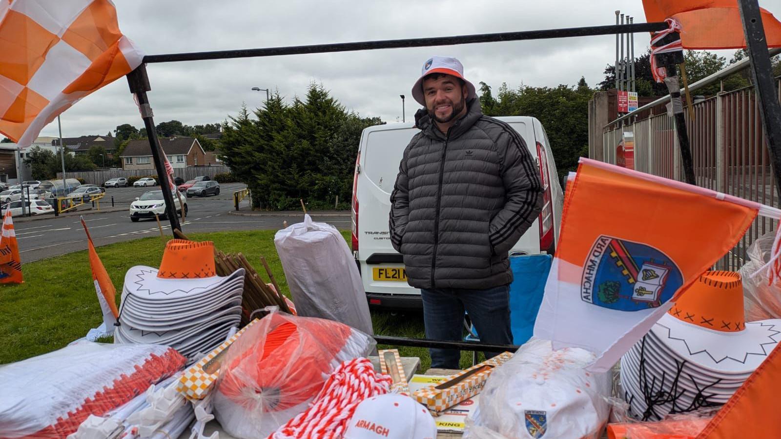 Man standing at a stall selling hats and flags