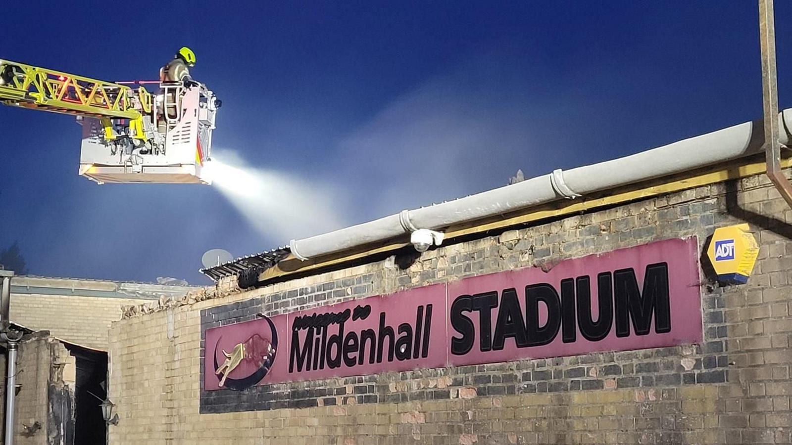 A firefighter sprays water on a section of the Mildenhall Stadium during a fire.