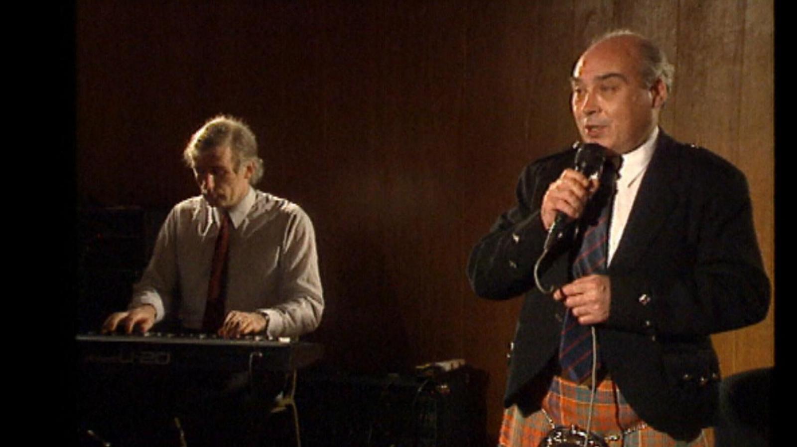 Dòmhnall MacRath a' seinn agus cuideigin a' cluich a' phiàno