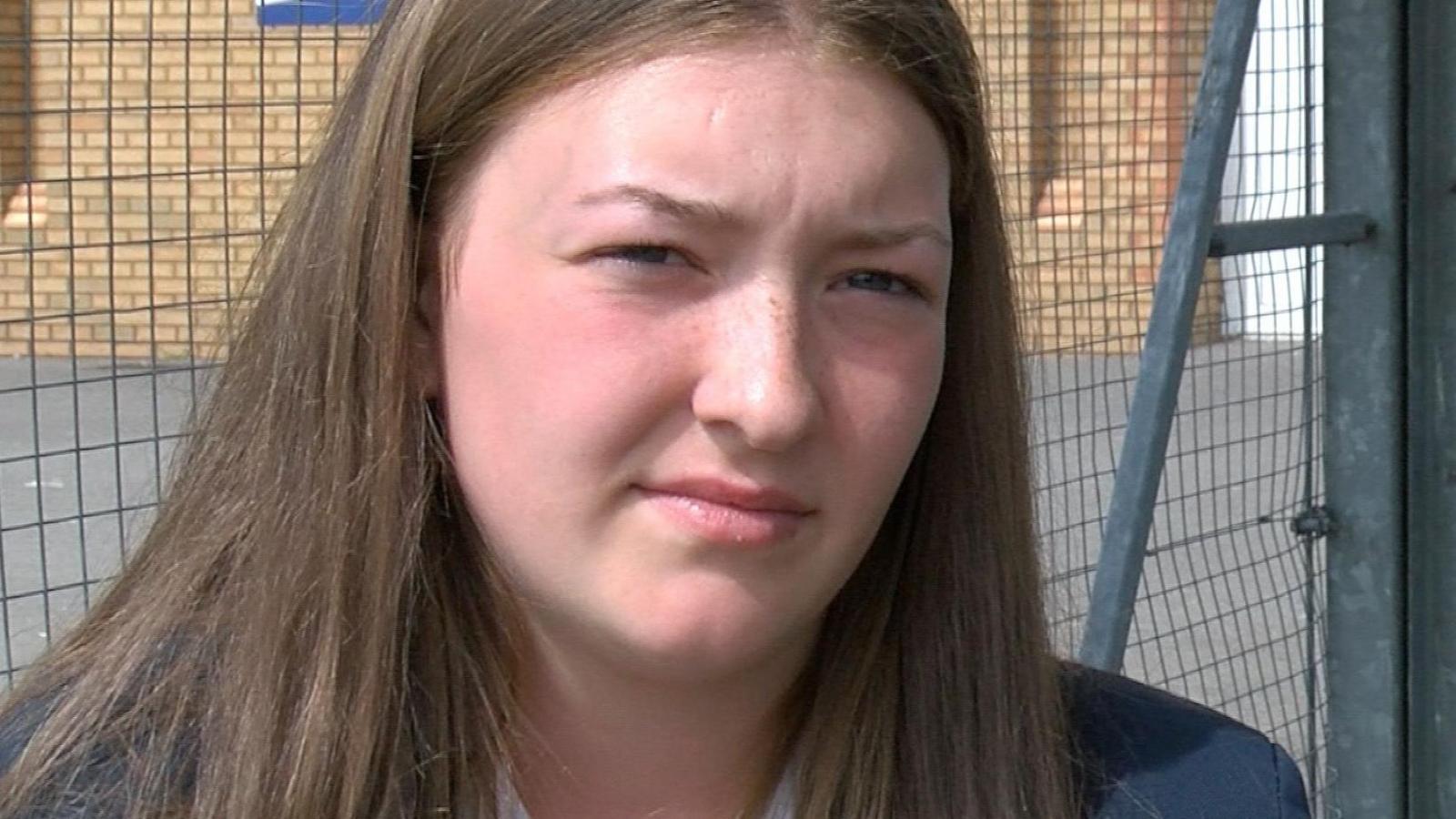 Portrait photo of Chanyta taken in 2021 when she was still at school. She has long brown hair, is wearing her school uniform and no make-up. It's taken in the school playground.