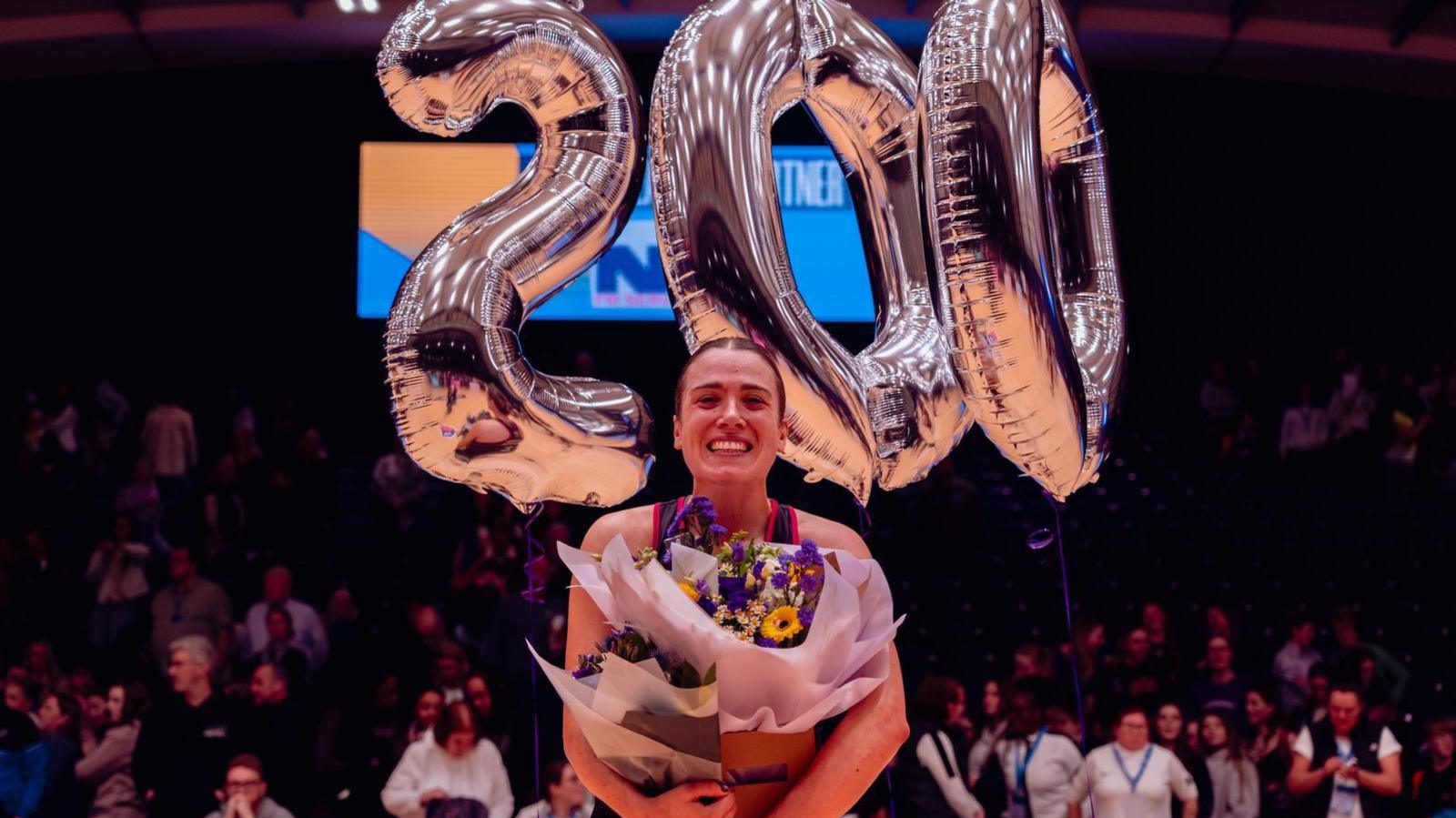 Nat Panagarry with flowers and silver balloons of the numbers 2, 0 and 0 to mark her 200th NSL match