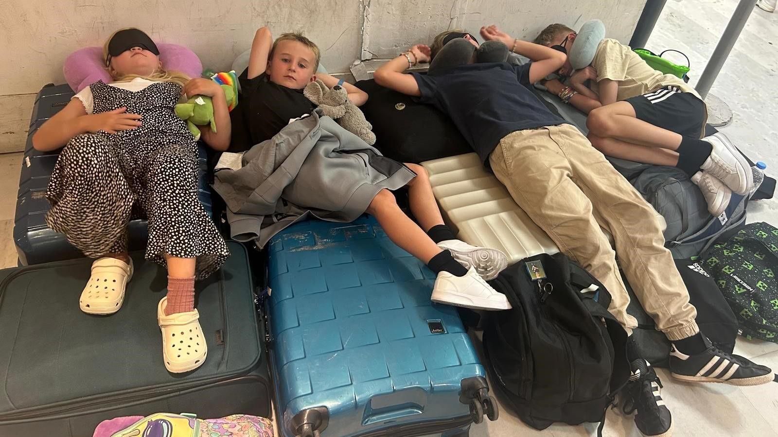 A group of four people lying on suitcases