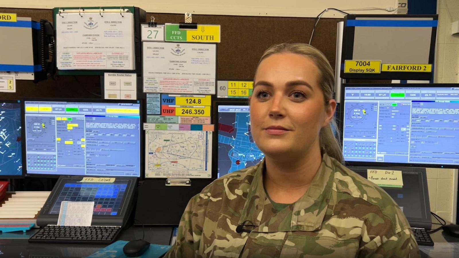 Flt Lt Bethany Horn in front of control panels, facing the camera. She looking at a reporter who is behind the camera. Her hair is in a pony tail.