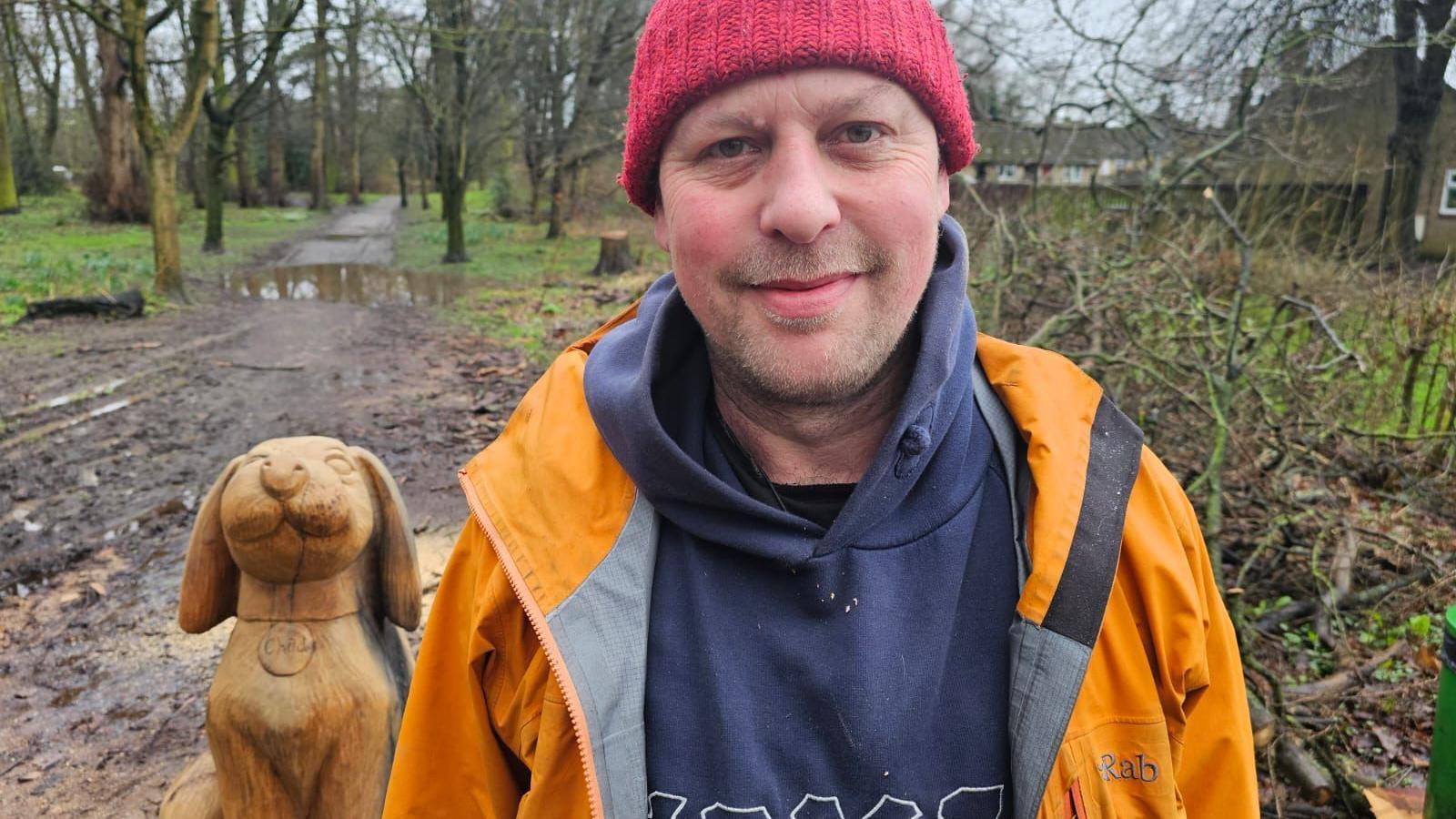 Sculptor Andy Frost standing next to his sculpture of a dog