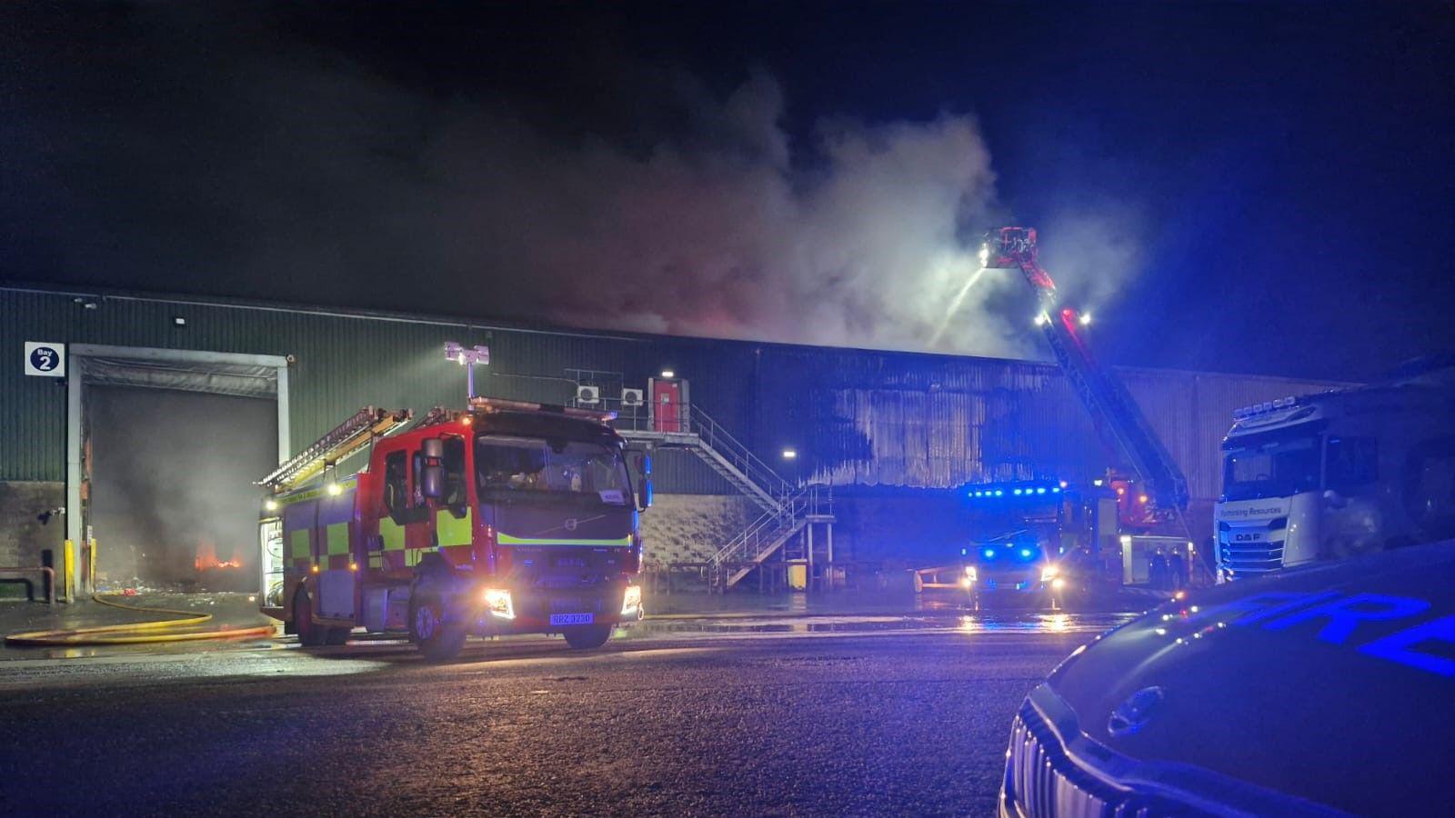 A fire engine sits outside a large warehouse a door which says 'Bay 2'