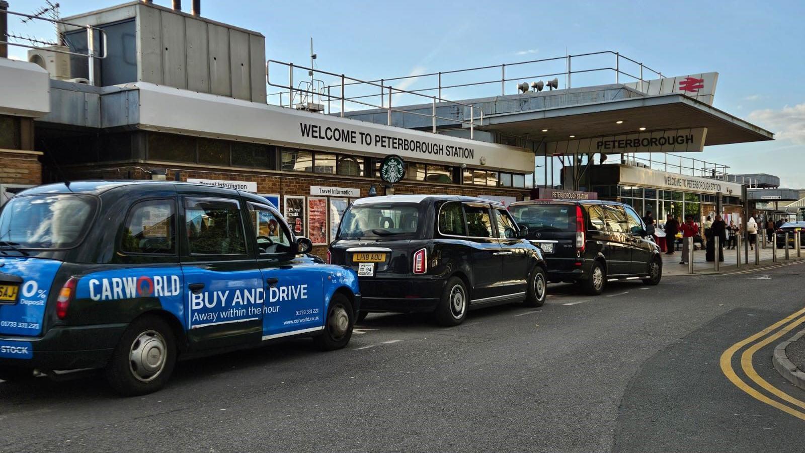 A row of black taxis outside Peterborough train station.