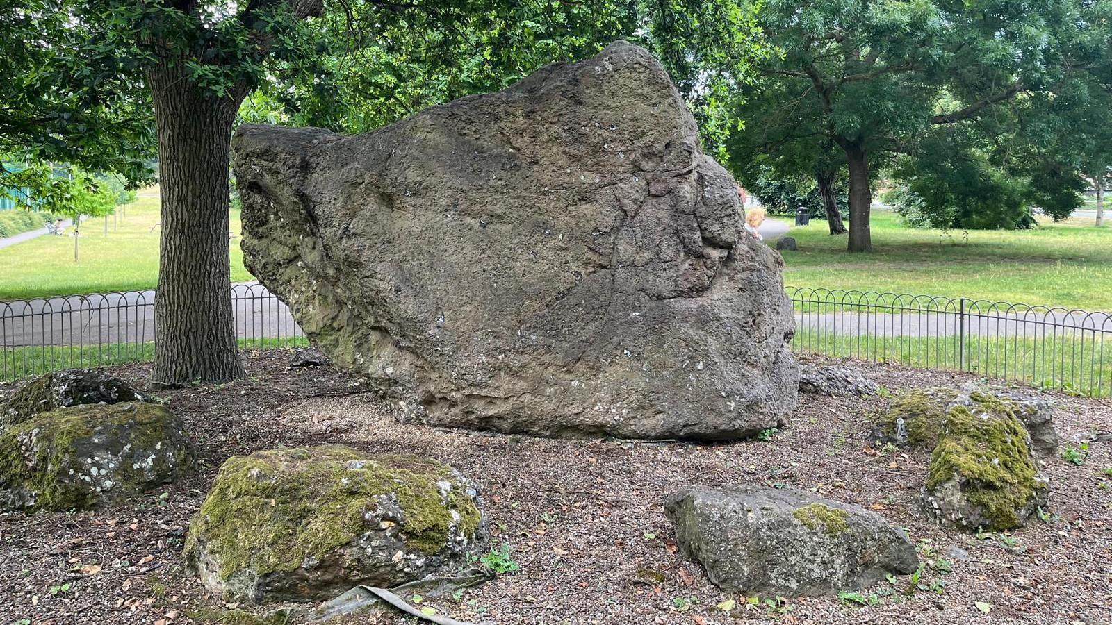A large rock with smaller rocks place around it. The big rock looks eerily like it has a human face.