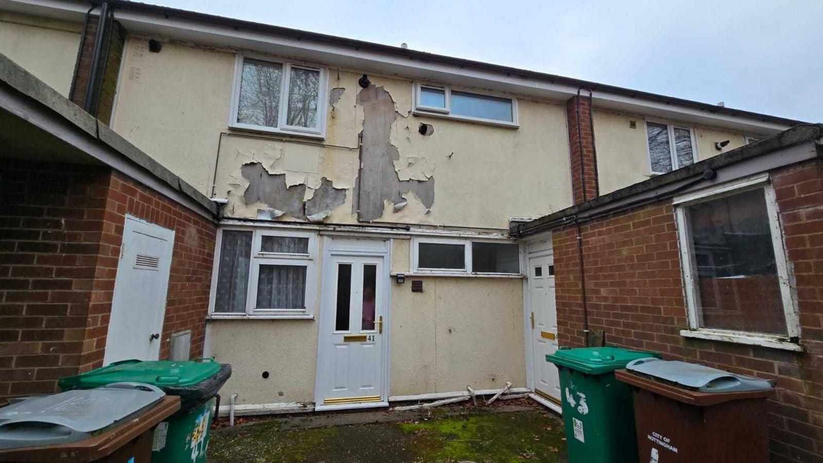 A dilapidated house where paint is coming away from the front of the property.