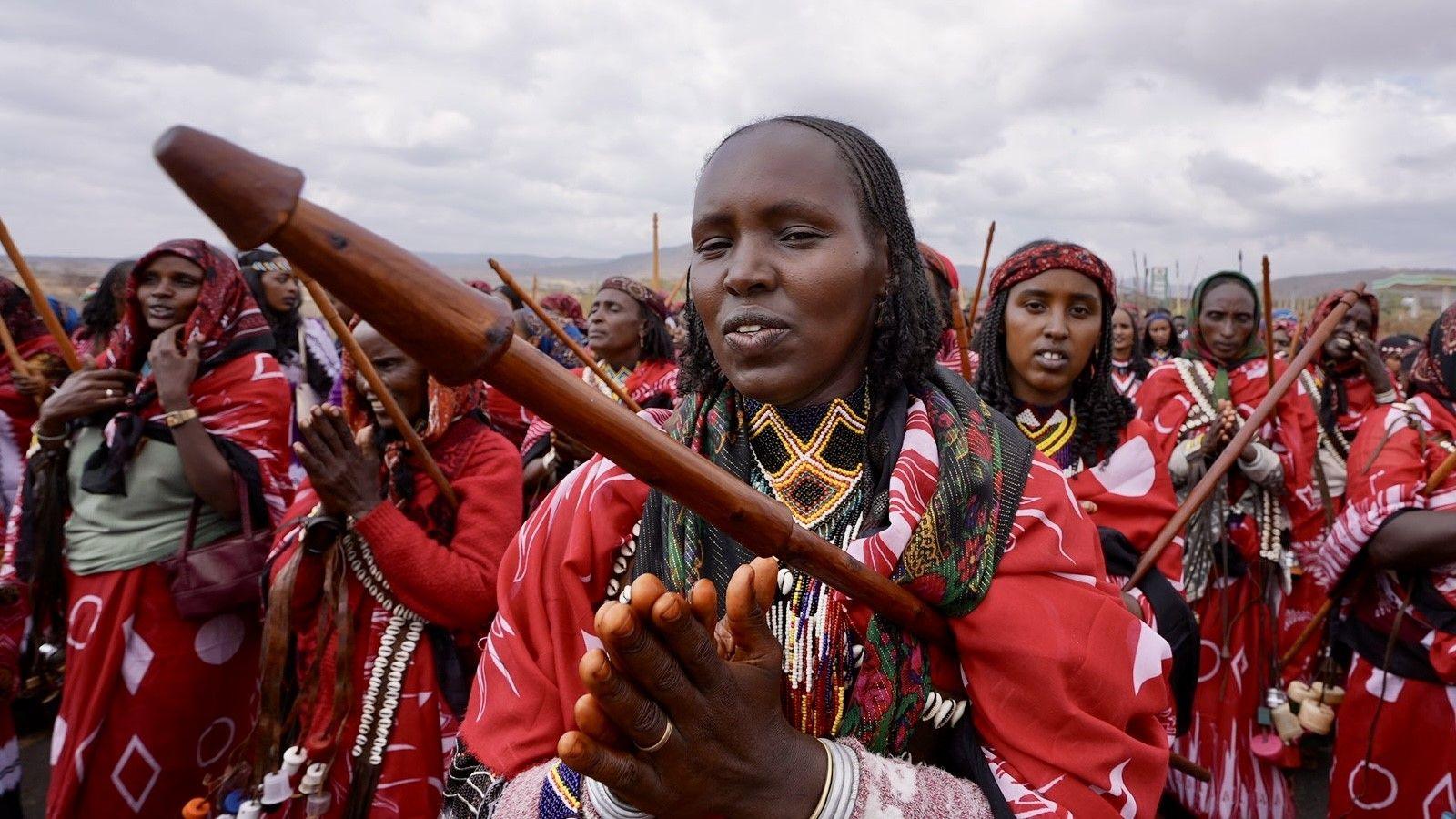 Women carry carved wooden sticks and march in matching red clothes.