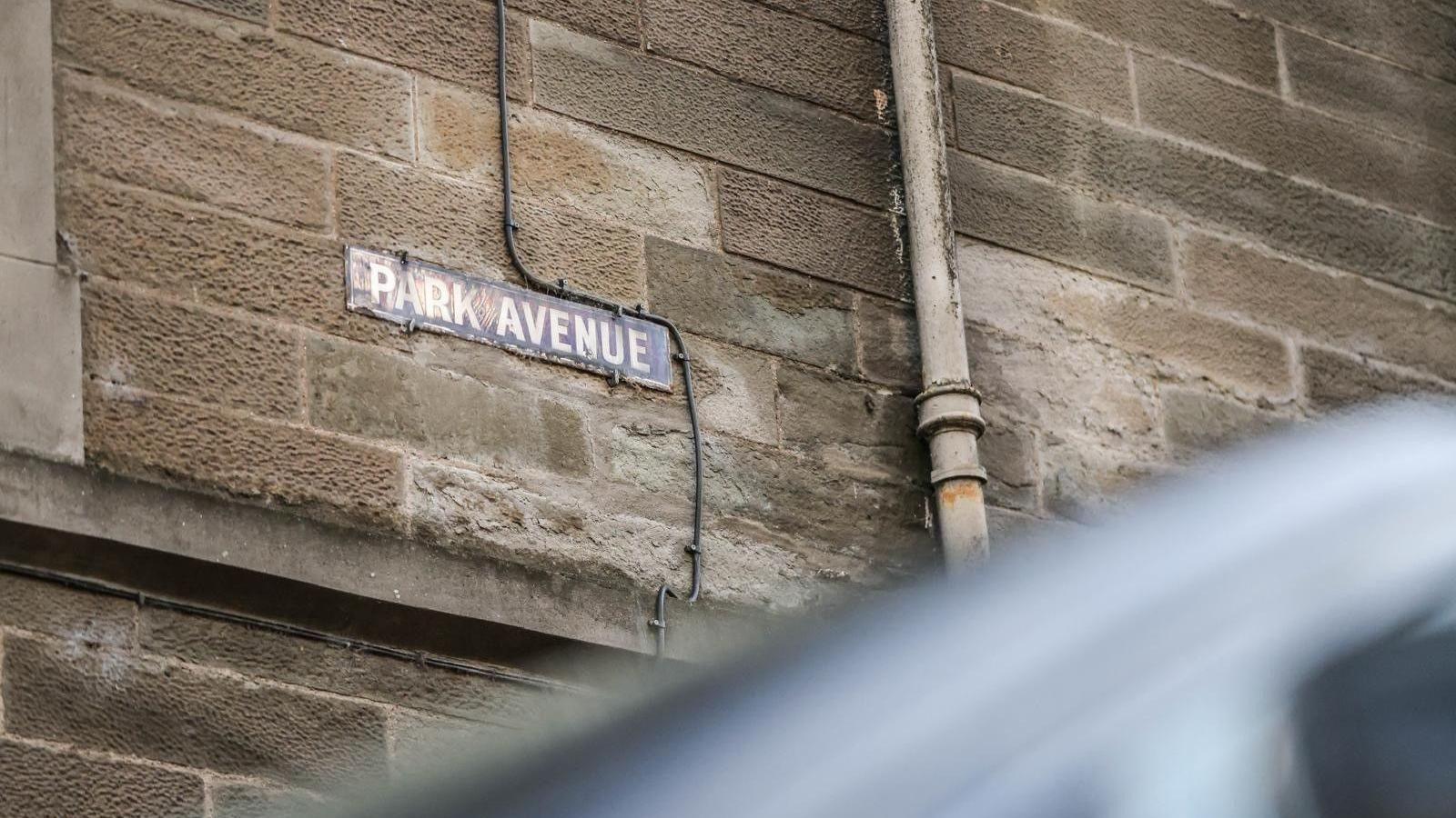 A street sign saying Park Avenue on a sandstone building wall