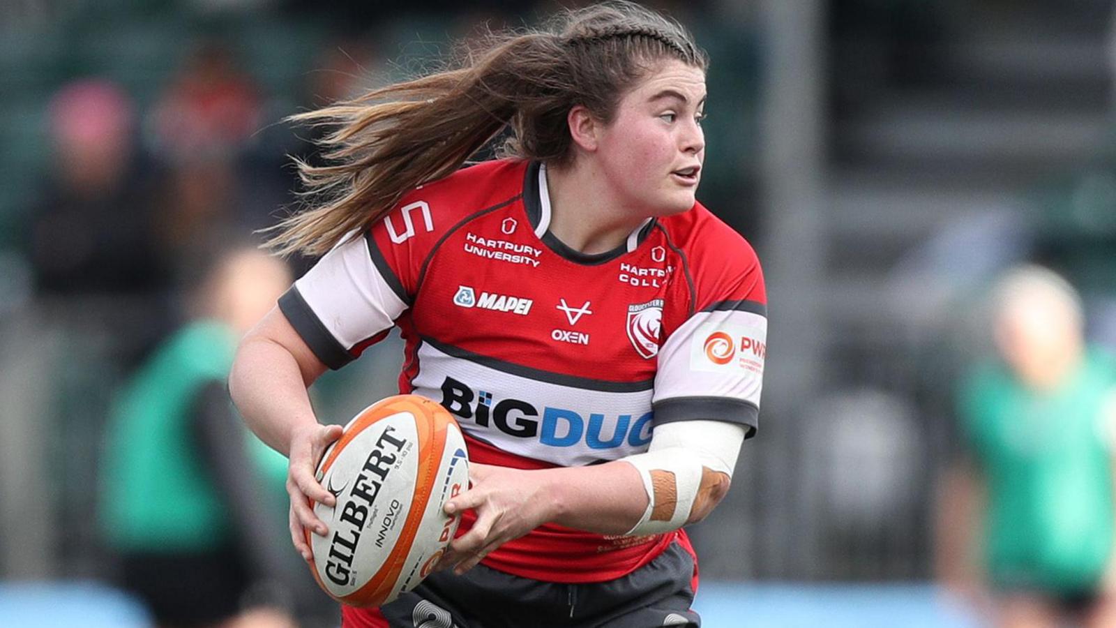 Maud Muir looks to the left as she runs with the ball in her hands at her right during a match for Gloucester-Hartpury