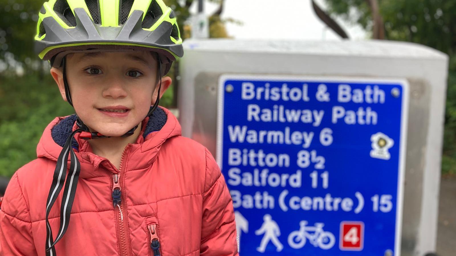 Pippin standing in front of a Bristol and Bath Railway Path cycle path sign