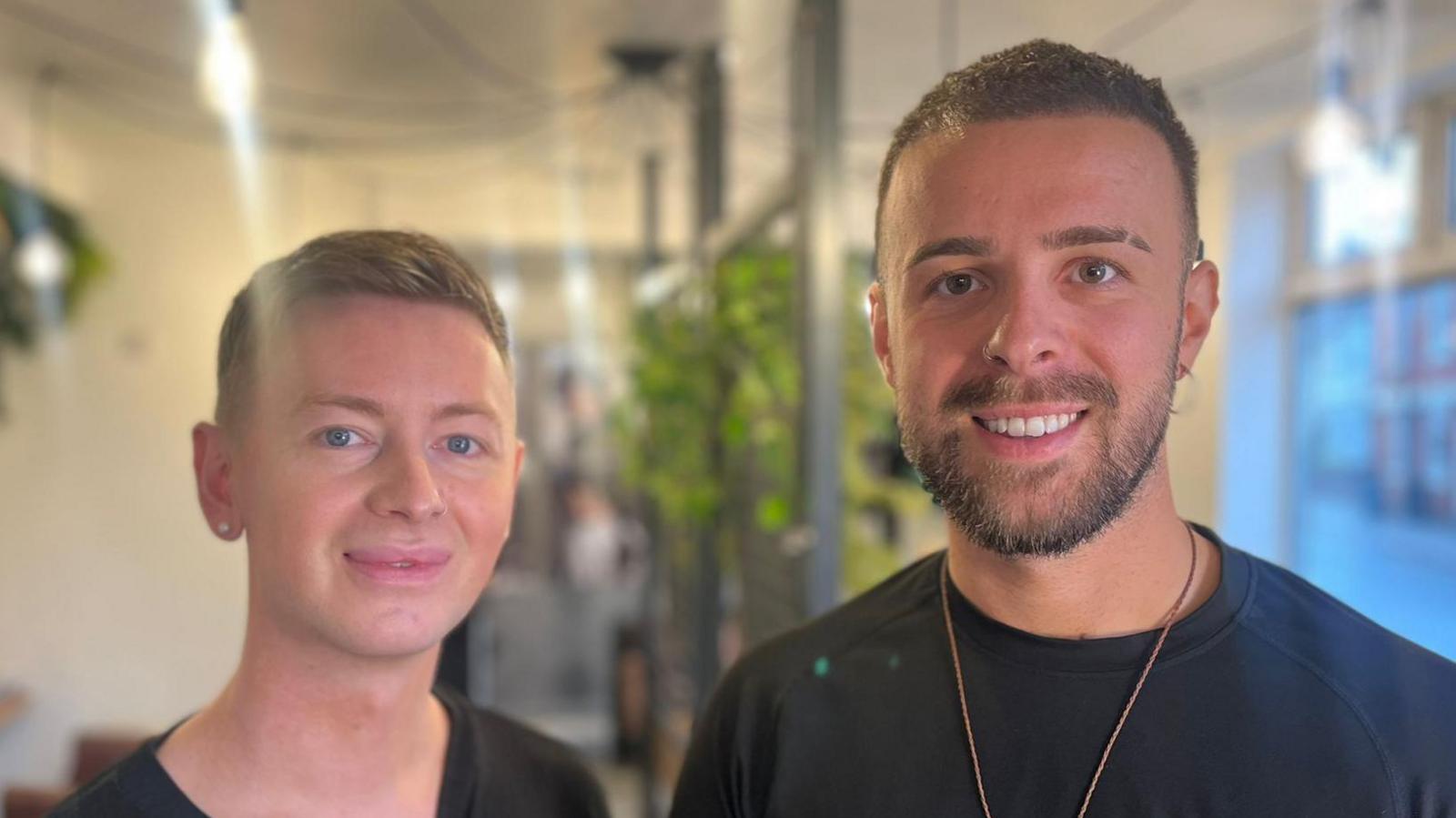 A photo showing two men smiling, looking directly at the camera
